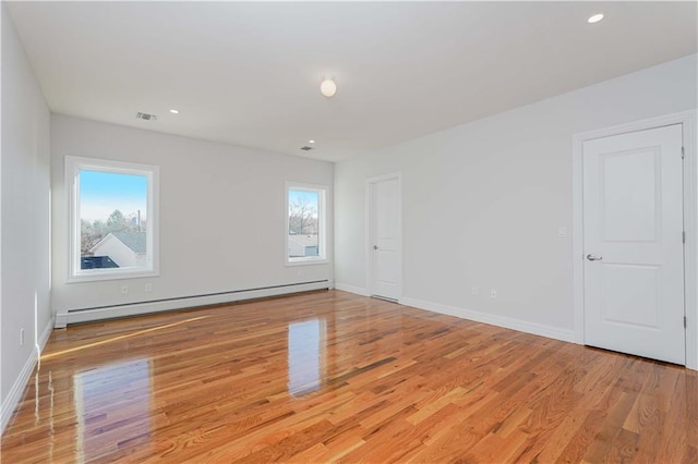 unfurnished room with a baseboard heating unit and light hardwood / wood-style flooring