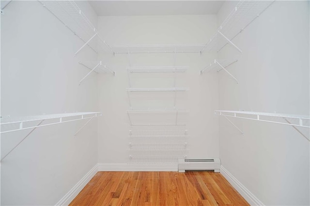 walk in closet with a baseboard heating unit and hardwood / wood-style floors