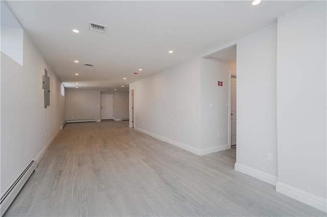 spare room with a baseboard heating unit, electric panel, and light hardwood / wood-style flooring