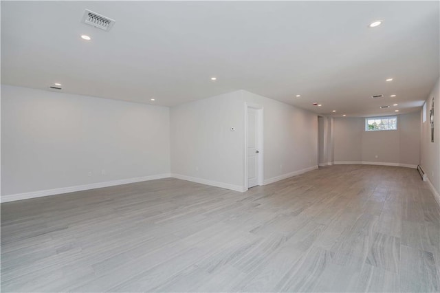 spare room featuring light wood-type flooring and a baseboard radiator