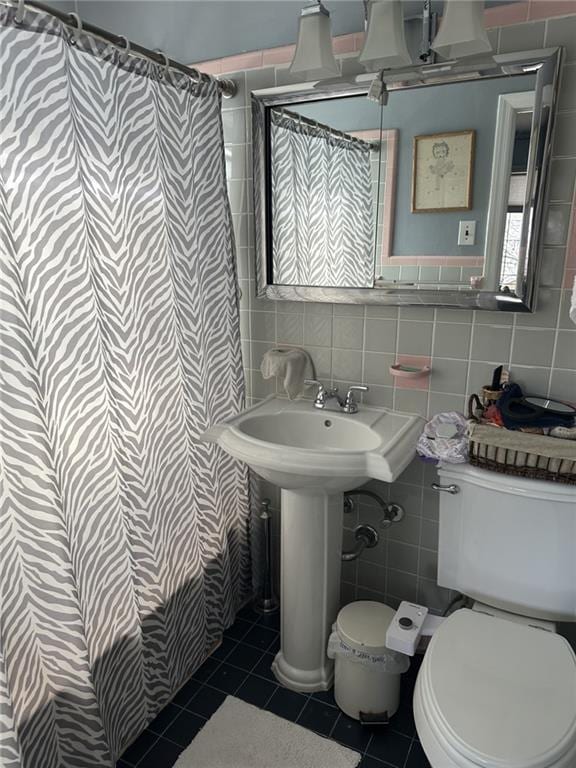 bathroom featuring tile patterned flooring, toilet, and tile walls