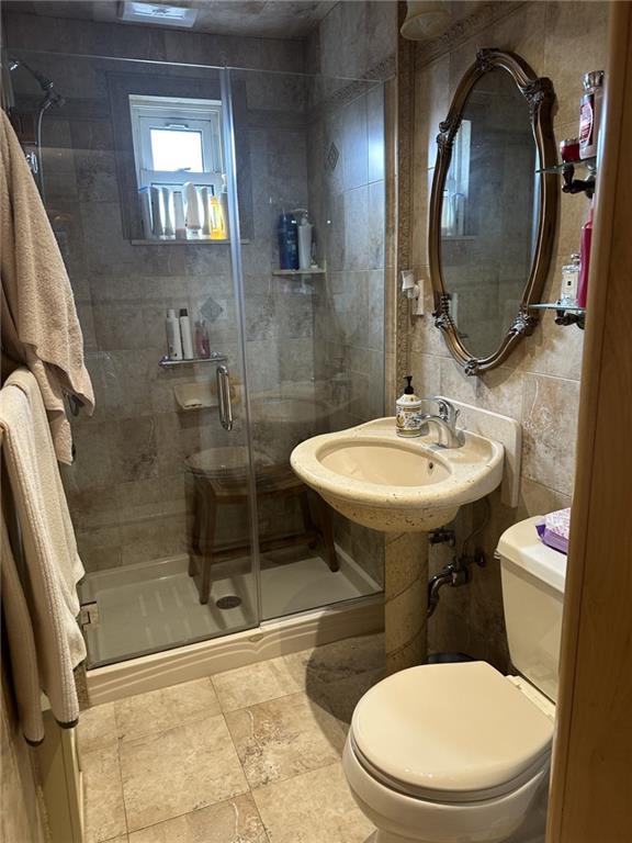 bathroom featuring sink, toilet, and a shower with door