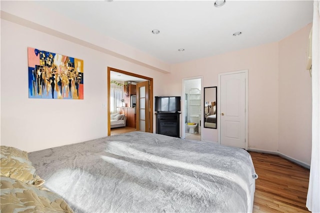 bedroom with connected bathroom and light hardwood / wood-style flooring