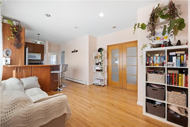 living room with light hardwood / wood-style flooring, french doors, and a baseboard heating unit