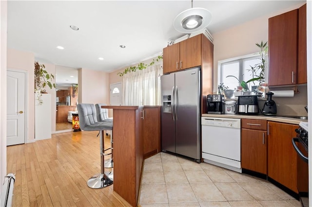 kitchen with baseboard heating, stainless steel fridge, a wealth of natural light, and white dishwasher