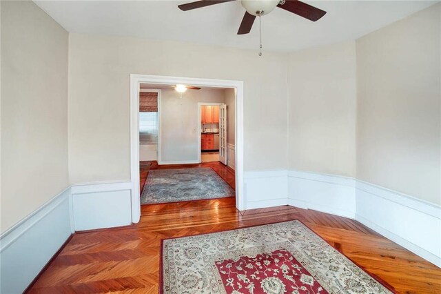 empty room featuring dark parquet flooring and ceiling fan