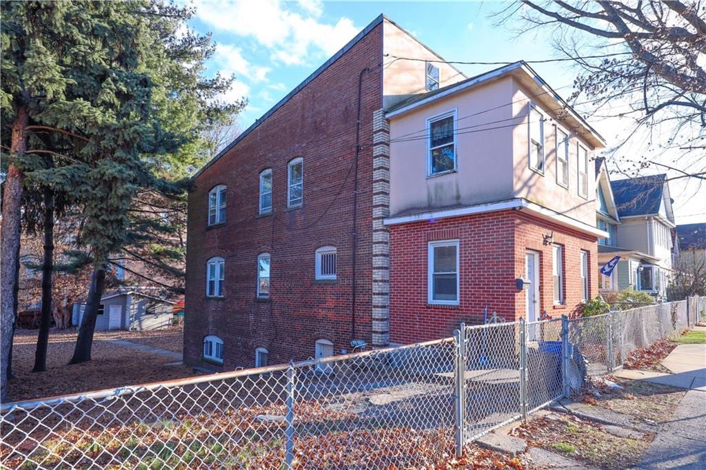 view of property exterior with brick siding and a fenced front yard