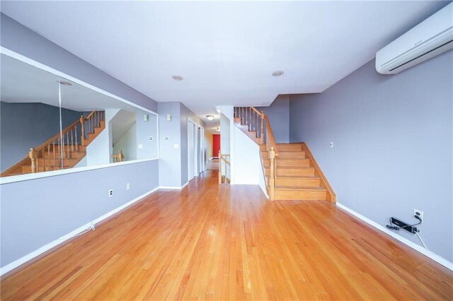 unfurnished living room with hardwood / wood-style flooring and an AC wall unit