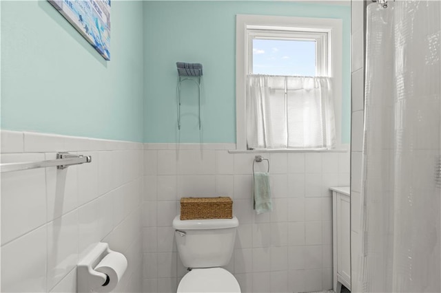 bathroom with toilet, tile walls, and curtained shower