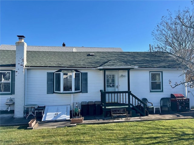 rear view of property with a lawn and roof with shingles