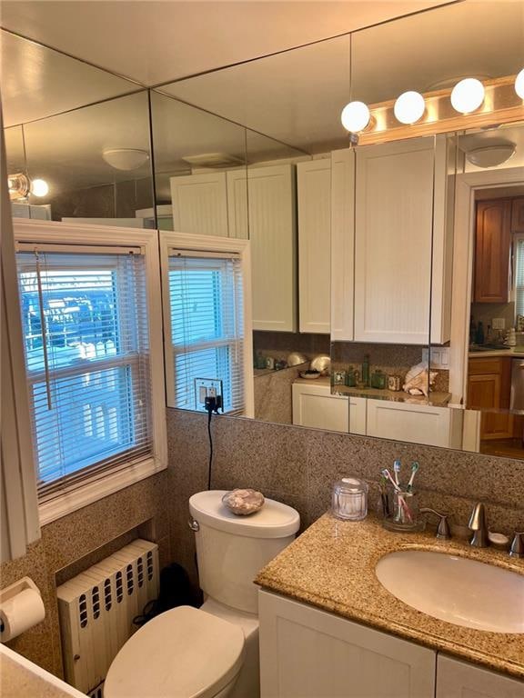 bathroom featuring radiator, toilet, tasteful backsplash, and vanity