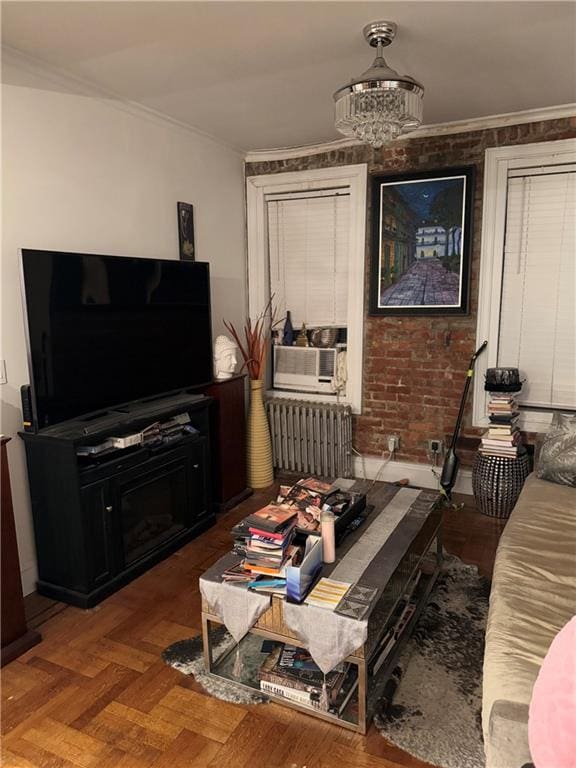 living room featuring parquet flooring, radiator heating unit, an inviting chandelier, and brick wall