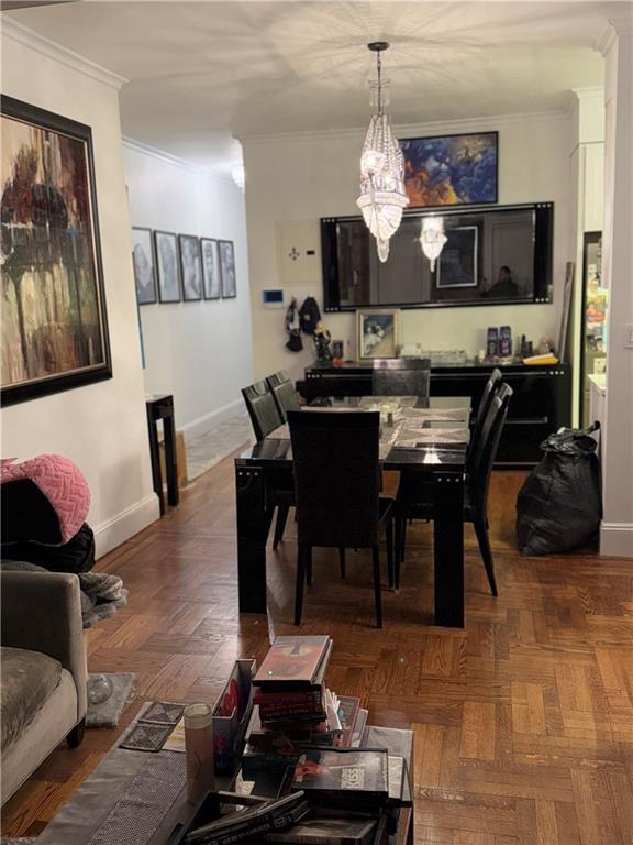 dining space featuring an inviting chandelier, dark parquet flooring, and crown molding