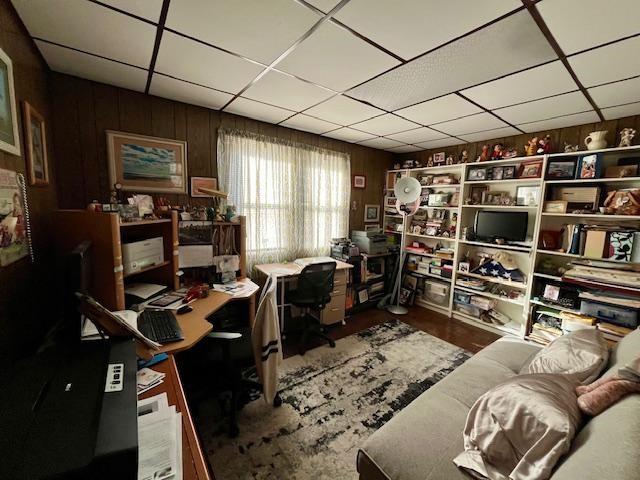 office space featuring hardwood / wood-style floors, a drop ceiling, and wood walls