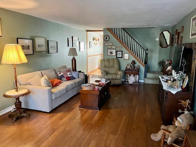 living room with stairway, wood finished floors, and baseboards