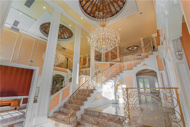 interior space featuring a chandelier, a towering ceiling, ornamental molding, and french doors