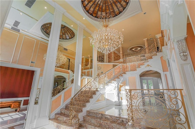 staircase featuring a chandelier, a high ceiling, crown molding, and visible vents