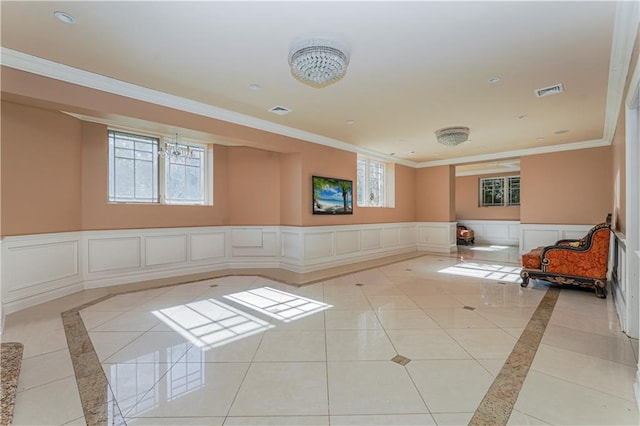 tiled empty room featuring an inviting chandelier and ornamental molding