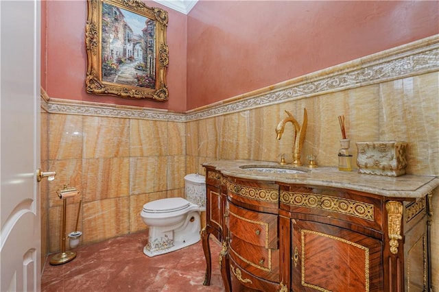 half bathroom with vanity, toilet, wainscoting, and tile walls