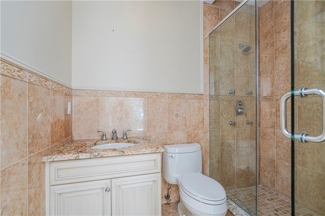 bathroom featuring walk in shower, vanity, tile walls, and toilet