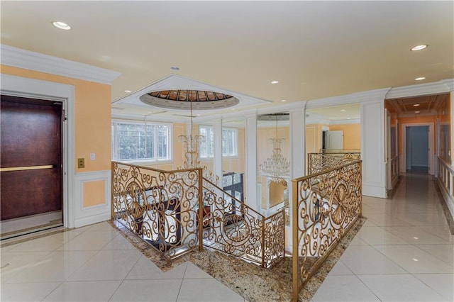 hallway featuring a decorative wall, tile patterned floors, ornamental molding, a wainscoted wall, and an upstairs landing