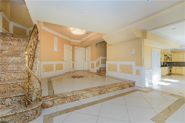foyer featuring a decorative wall, crown molding, stairs, and light tile patterned floors