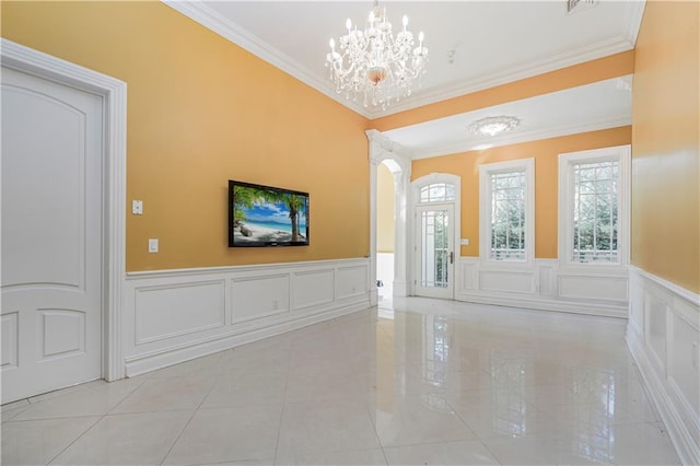 entrance foyer featuring ornamental molding, a wainscoted wall, an inviting chandelier, and a decorative wall