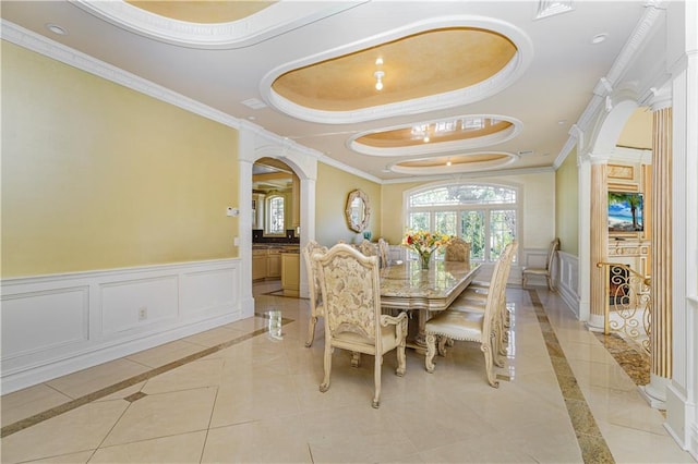 dining space featuring a raised ceiling, ornate columns, and ornamental molding