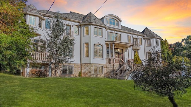 view of front of home with stairs, a balcony, and a yard