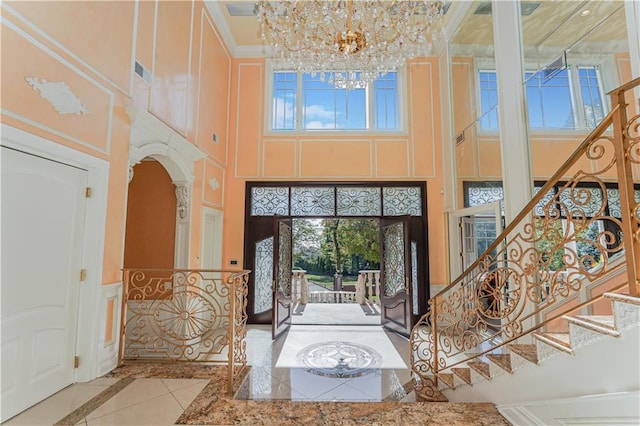 entryway with a high ceiling, stairway, a decorative wall, and a healthy amount of sunlight