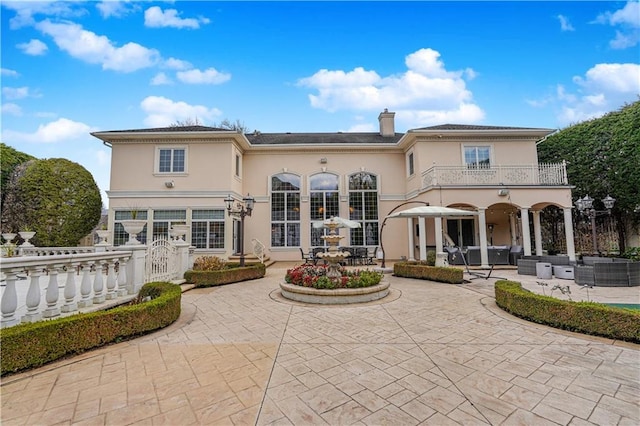 rear view of house with a balcony, a patio area, outdoor lounge area, stucco siding, and fence private yard