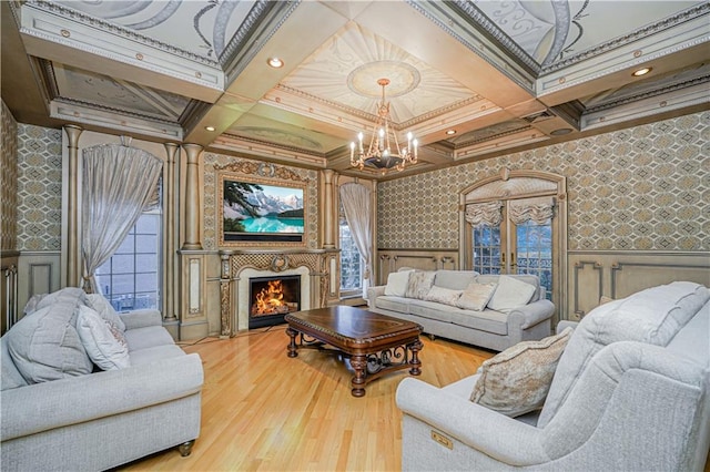 living area with a chandelier, wallpapered walls, wood finished floors, and coffered ceiling