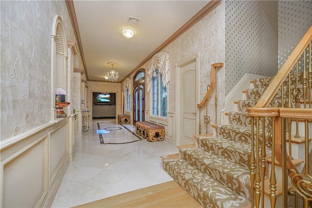 interior space with an inviting chandelier, stairs, wainscoting, ornamental molding, and visible vents