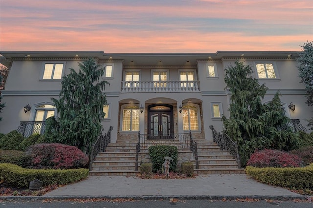 view of front of home featuring french doors, a balcony, and covered porch