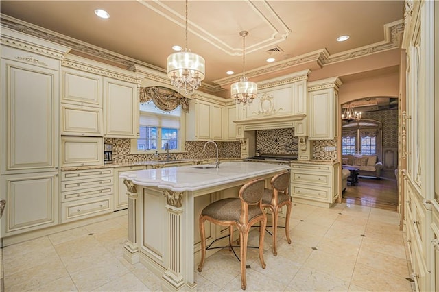 kitchen with cream cabinets, a center island with sink, a kitchen breakfast bar, and decorative light fixtures