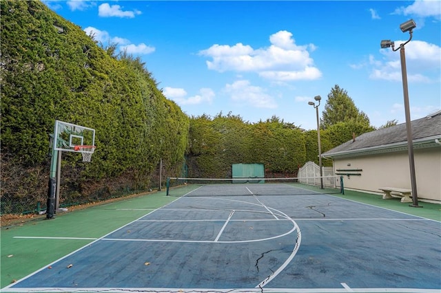 view of basketball court with a tennis court, fence, community basketball court, and a view of trees