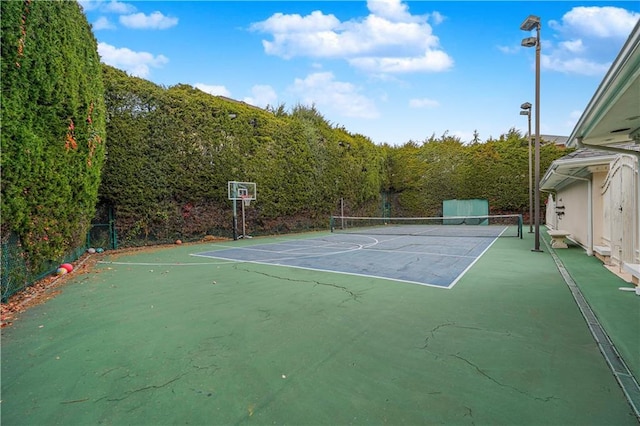 view of sport court featuring a tennis court, a view of trees, and fence
