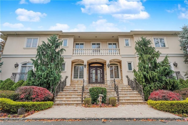 view of front of house with stairs, stucco siding, french doors, and a balcony