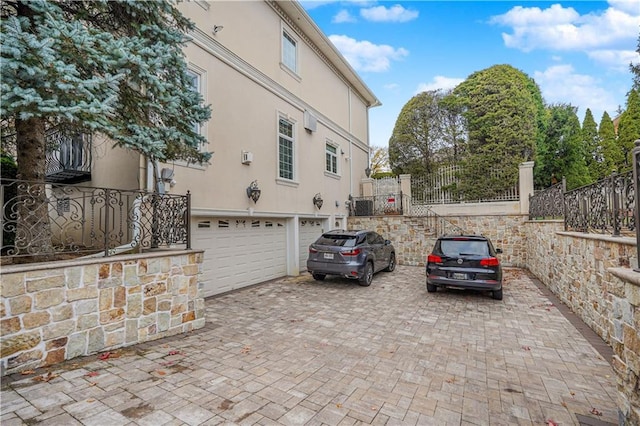view of home's exterior with a garage, fence, stucco siding, and decorative driveway