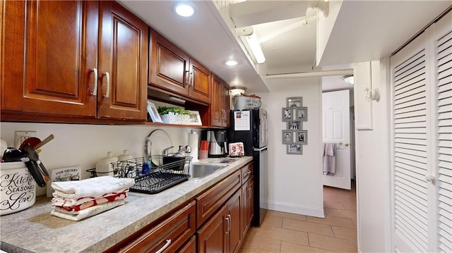 kitchen featuring light tile patterned flooring, baseboards, freestanding refrigerator, recessed lighting, and light countertops