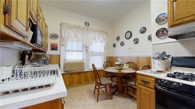 kitchen with crown molding, black appliances, brown cabinets, a wainscoted wall, and light countertops