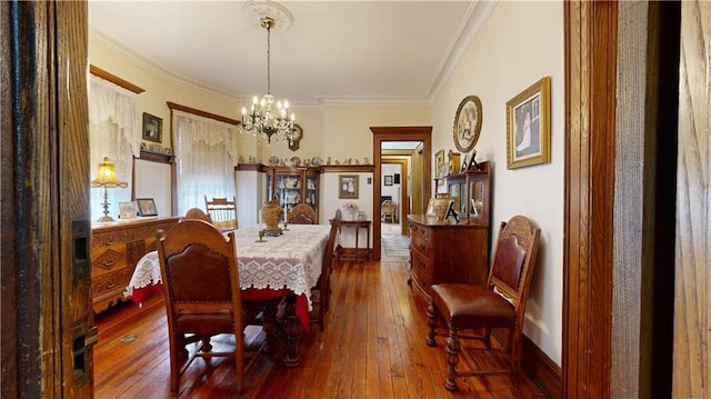 dining room with hardwood / wood-style flooring, ornamental molding, and a notable chandelier