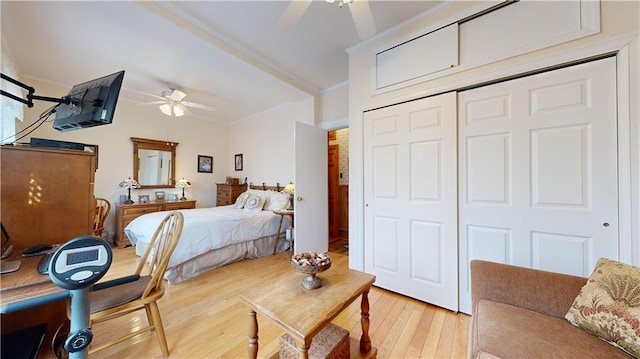 bedroom featuring hardwood / wood-style flooring, ceiling fan, crown molding, and a closet