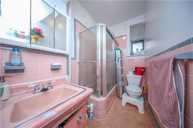 full bathroom with tile patterned floors, sink, bath / shower combo with glass door, tile walls, and toilet