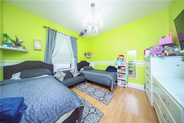 bedroom with light hardwood / wood-style floors and a notable chandelier