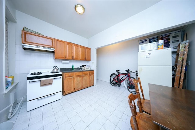 1830 81st St, Brooklyn, NY 11214 - kitchen with under cabinet range hood, dark countertops, light tile patterned floors, white appliances, and brown cabinetry