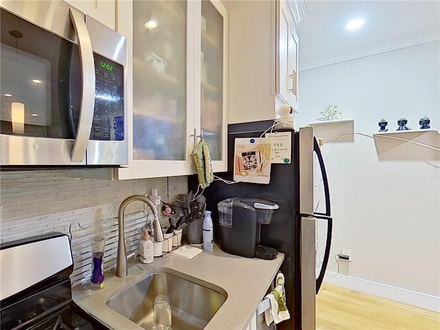 kitchen with sink, white cabinets, light hardwood / wood-style flooring, and appliances with stainless steel finishes