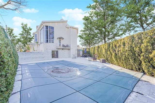 exterior space featuring a balcony, a patio, and a covered pool