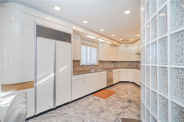 kitchen featuring paneled refrigerator, sink, white cabinetry, stainless steel dishwasher, and tasteful backsplash