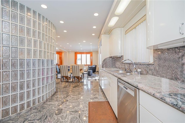 kitchen with dishwasher, light stone countertops, sink, white cabinetry, and tasteful backsplash